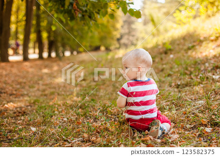 One-year-old little boy exploring the world in an autumn forest One-year-old little boy exploring the world in an autumn forest 123582375