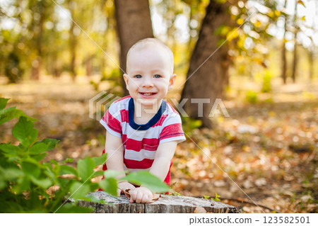 Ten-month-old baby sitting on a felled tree in the autumn forest 123582501
