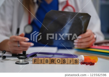 The doctor analyzes the fibrosis Xray with a stethoscope while preparing patient prescriptions 123582596