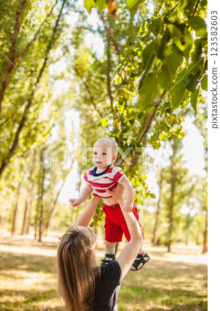 Young mother playing and tossing her one-year-old son in the park on a sunny day 123582603