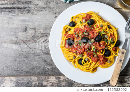 Italian Pasta puttanesca with tomato sauce, capers, and black olives on wooden table. Top view. Copy space Italian Pasta puttanesca with tomato sauce, capers, and black olives on wooden table. Top view. Copy space 123582992