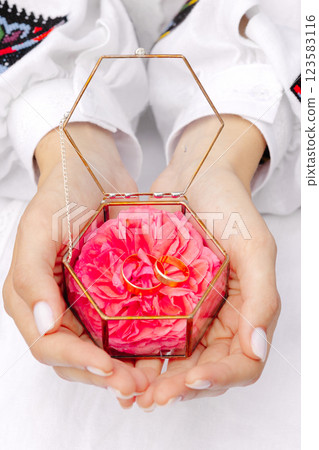 Woman holding glass box with wedding rings and pink rose petals 123583116