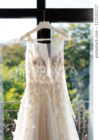 Elegant white wedding dress hanging in hotel room window 123583117