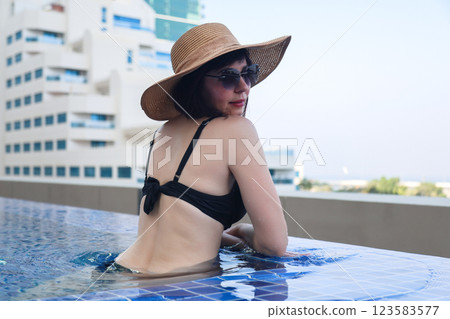 Woman waist deep in warm heated swimming pool of luxury hotel 123583577