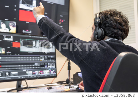 A television director in a broadcast control room, actively guiding a live production. Surrounded by A television director in a broadcast control room, actively guiding a live production. Surrounded by 123583868