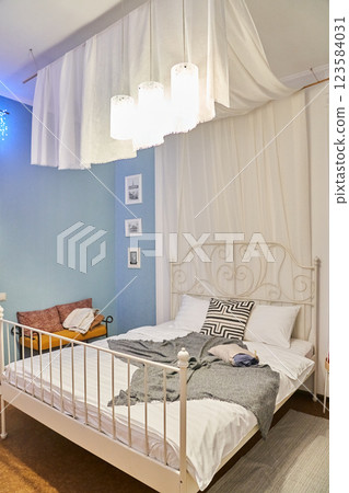 Vintage metal bed in a hotel room. A room with a copy space with blue walls and bright lighting. High quality photo 123584031