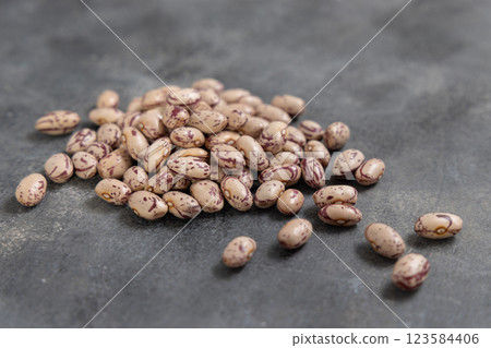 Pile of dried raw uncooked pinto beans on dark gray table closeup. Traditional Latin American legumes 123584406