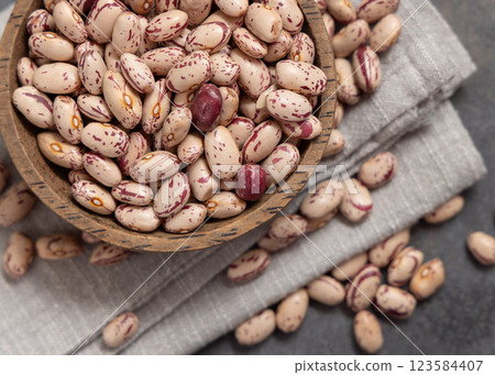 Wooden bowl full of dried pinto beans on napkin on gray top view. Traditional Latin American legumes 123584407
