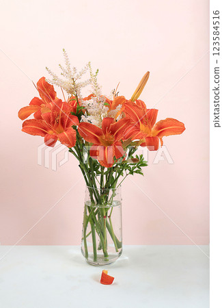 Abstract floral composition, background, minimal holiday concept with flowers, spring summer banner. Lily and chamomile flowers in a vase with shadows on a sunny table, postcard with space for text. 123584516