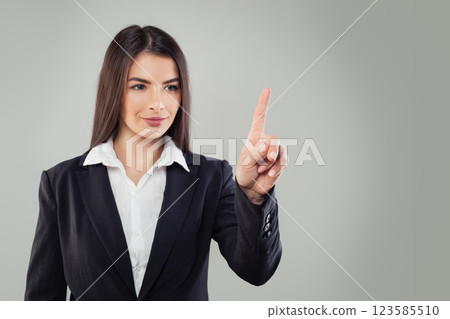 Positive business woman in black suit pointing finger up or pushing button on white background Positive business woman in black suit pointing finger up or pushing button on white background 123585510