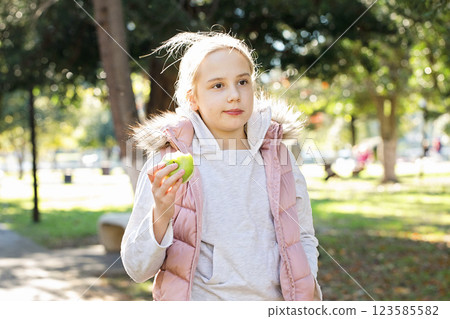 Beautiful kid holding green apple. Young girl in park, outdoors portrait Beautiful kid holding green apple. Young girl in park, outdoors portrait 123585582