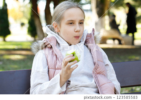Funny kid holding green apple. Young girl in park, outdoors portrait Funny kid holding green apple. Young girl in park, outdoors portrait 123585583