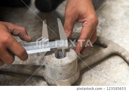 Close up scene the machine operator measuring inside dimension of cast iron parts by Vernier caliper. 123585653
