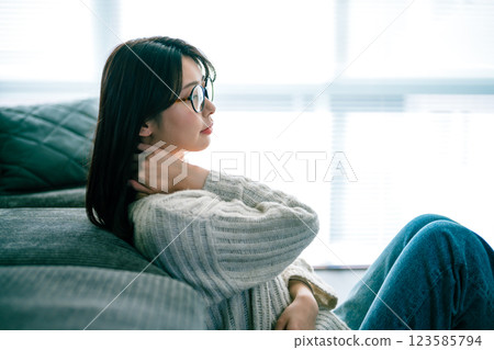 女人在沙發上放鬆，雙手放在脖子上 123585794