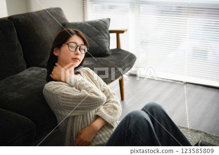 一名女子靠在沙發上，摀住脖子 123585809