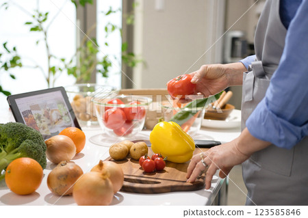 Middle woman cooking while looking at a tablet 123585846
