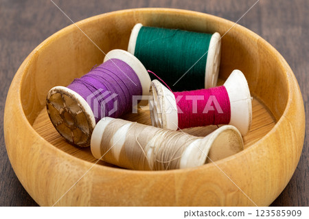 Spools of old cotton thread in different colors in a light brown wooden box. Ready to sew and craft Spools of old cotton thread in different colors in a light brown wooden box. Ready to sew and craft 123585909