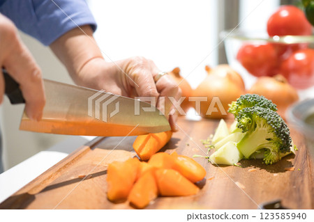 Hands of a middle-aged woman cutting vegetables 123585940