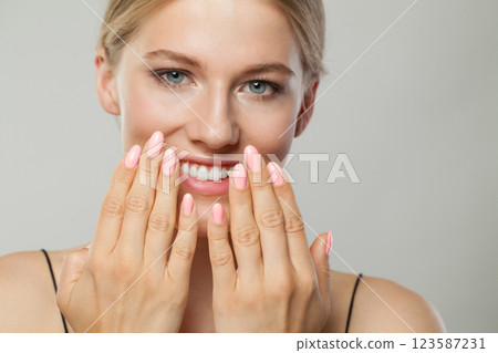 Close-up studio portrait of beautiful woman with pink nail polish on her hand 123587231