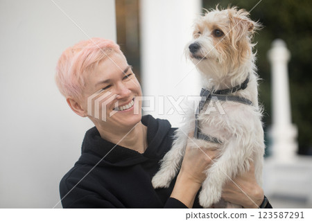 Laughing woman having fun playing with pet dog outdoors 123587291