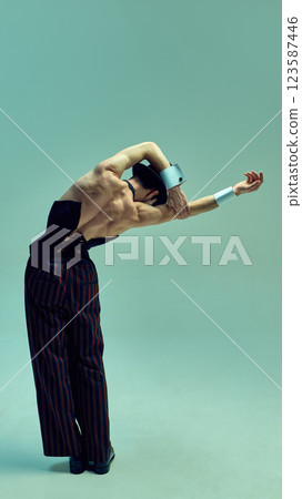 Expressive dancer bending arms in sculptural motion, emphasizing fluidity and structure in retro-inspired ensemble against soft minimal backdrop. Expressive dancer bending arms in sculptural motion, emphasizing fluidity and structure in retro-inspired ensemble against soft minimal backdrop. 123587446