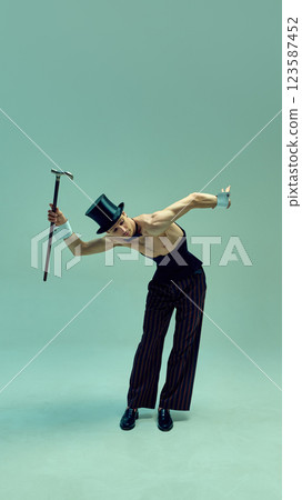 Retro dressed man tilting forward with cane, evoking essence of old-fashioned charm in structured corset and refined accessories against muted background. Retro dressed man tilting forward with cane, evoking essence of old-fashioned charm in structured corset and refined accessories against muted background. 123587452