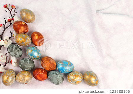 Natural marble Easter eggs, dyed with hibiscus tea, onion peel and curcumin, with a branch of sakura on a kitchen tablecloth. Easter celebration concept, holiday card and ideas for preparing for the 123588106
