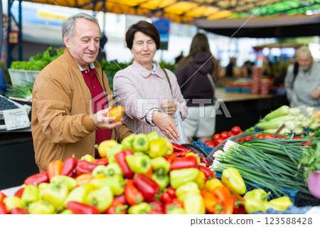 Elderly casual man and woman customers couple buying fresh bell peppers at indoor market 123588428