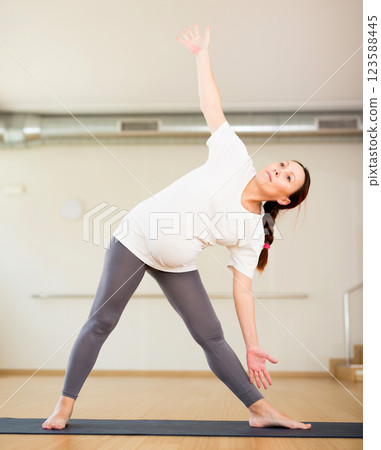 Pregnant woman is engaged in yoga. Elongated Triangle Pose or Utthita Trikonasana Pregnant woman is engaged in yoga. Elongated Triangle Pose or Utthita Trikonasana 123588445