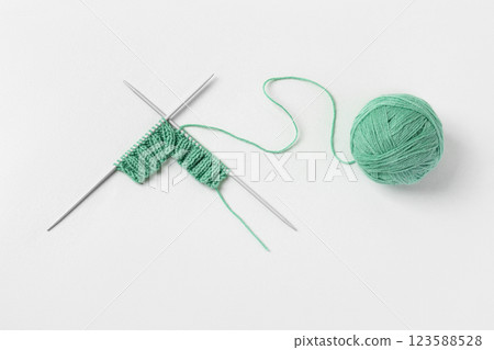 Green knitted wool on gray background with knitting needles for knitting warm clothes and hobbies needlework Green knitted wool on gray background with knitting needles for knitting warm clothes and hobbies needlework 123588528