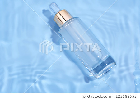 Bottle with moisturizing serum in water on blue background. 123588552