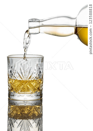 Pouring whiskey from a bottle into a glass on a white background. 123588818