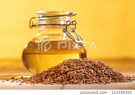 Organic flaxseed oil in glass jar with whole flaxseeds on vibrant orange background 123589385