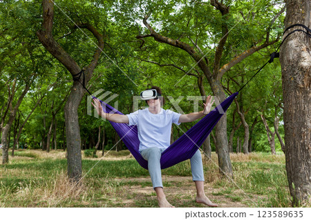 A young guy with curly hair is relaxing on a hammock on a hot summer day. A young guy with curly hair is relaxing on a hammock on a hot summer day. 123589635