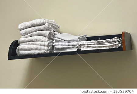 Clean towels and pillowcases lined up on a shelf mounted on the wall 123589704