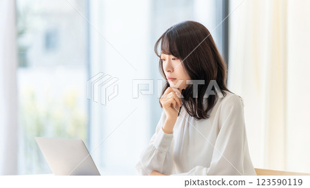 A woman/businesswoman thinking while looking at a computer screen A woman/businesswoman thinking while looking at a computer screen 123590119