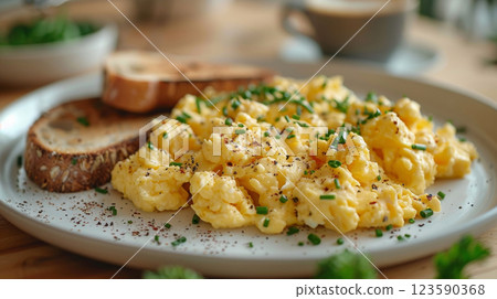 Close-up of perfectly cooked scrambled eggs, lightly seasoned, on a classic white plate against a cozy kitchen backdrop 123590368