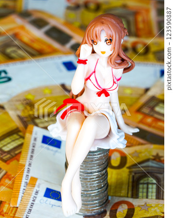 A young woman doll figurine in a swimsuit sits on a pile of coins on a background of euro banknotes 123590887