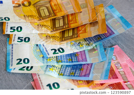 Scattered 10, 20 and 50 variegated euro banknotes on a gray background, low wage income concept Scattered 10, 20 and 50 variegated euro banknotes on a gray background, low wage income concept 123590897