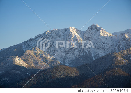 Stunning winter landscape of Zakopane, Poland, featuring the snow-covered Tatra Mountains at sunset. The picturesque alpine town, surrounded by forests and peaks, offers breathtaking views and is a po 123591084