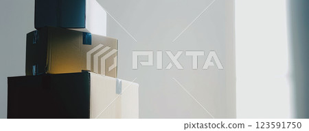 Boxes are stacked by a bright window, casting soft shadows on the light wall. Concept of delivery and storage. 123591750