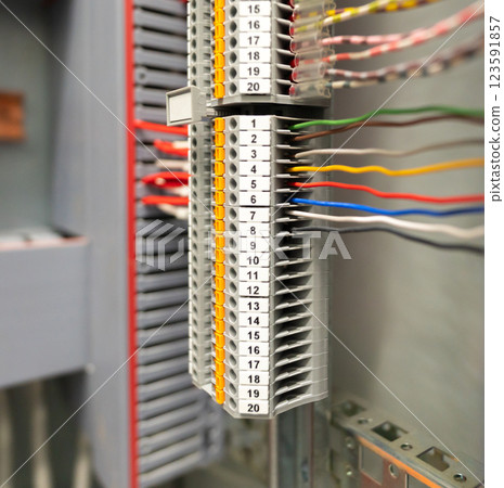 Close-up of a terminal block with numbered connections and organized wiring inside an electrical panel 123591857