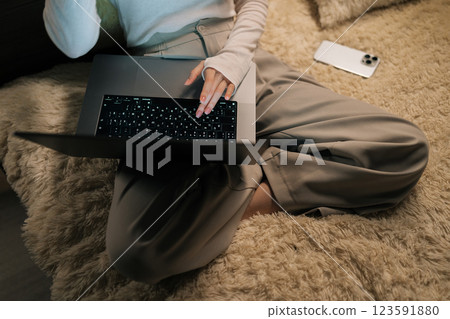 Close-up top view of unrecognizable female freelancer working typing on laptop keyboard sitting in bed at evening, creating cozy atmosphere for late-night work or online leisure activities. Close-up top view of unrecognizable female freelancer working typing on laptop keyboard sitting in bed at evening, creating cozy atmosphere for late-night work or online leisure activities. 123591880