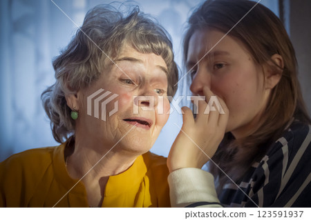 Girl tells news or secret to her smiley grandmother. 123591937