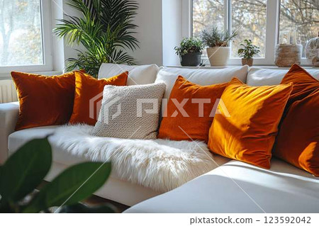 Modern, bright living room with a white sectional sofa, fluffy throw blanket, and orange velvet pillows Modern, bright living room with a white sectional sofa, fluffy throw blanket, and orange velvet pillows 123592042