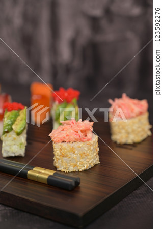 Asian food. Assorted sushi roll with rice and fish on wooden serving board. Dark black texture background with copy space. Close up. Japan menu 123592276