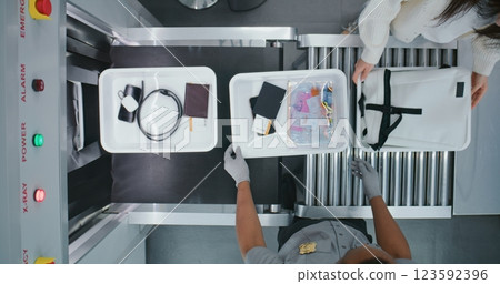 Diverse People, Travelers Putting Personal Items in Plastic Trays for X-ray Scanning on Conveyor Belt Diverse People, Travelers Putting Personal Items in Plastic Trays for X-ray Scanning on Conveyor Belt 123592396