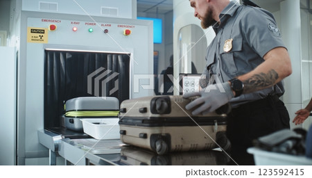 TSA Worker Putting Luggage and Personal Items in Trays on Conveyor Belt with X-ray Metal Detector TSA Worker Putting Luggage and Personal Items in Trays on Conveyor Belt with X-ray Metal Detector 123592415