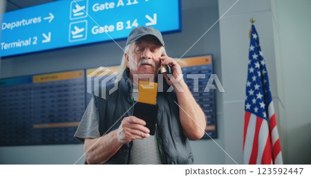 Crowded Airport Terminal: Elderly Man Holding Plane Ticket, Talking by Mobile Phone Crowded Airport Terminal: Elderly Man Holding Plane Ticket, Talking by Mobile Phone 123592447