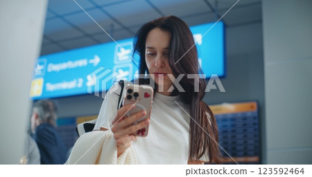 Airport Terminal: Woman Scanning Plane Ticket Using Smartphone to Check Flight Information 123592464